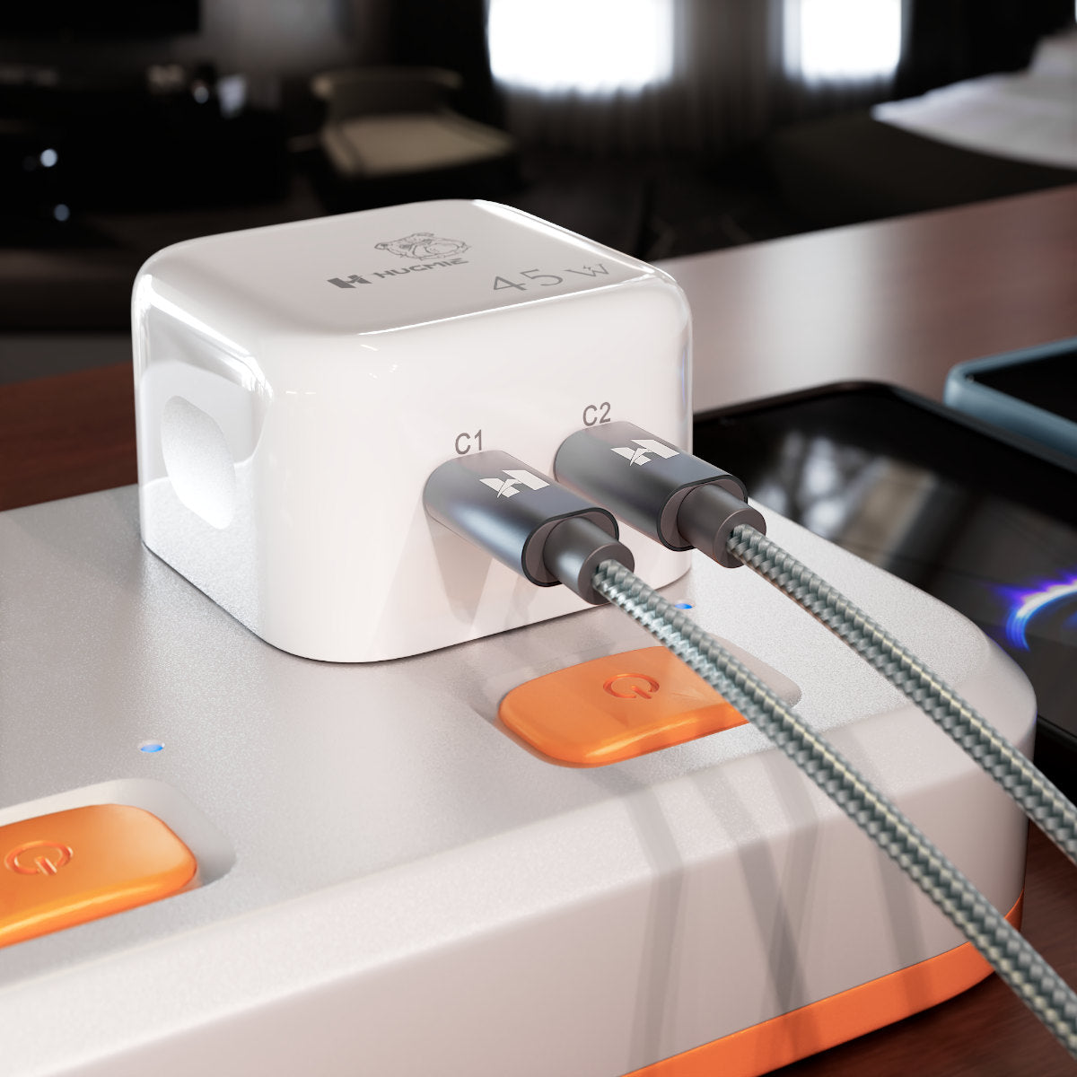 Close-up of Hugmie PD 45W Fast Charger plugged into a power strip. Dual USB-C ports ensure fast and efficient charging.