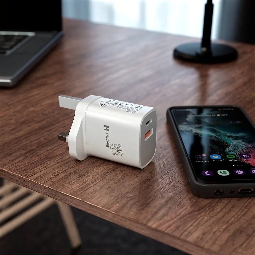 Hugmie FP01 fast charger placed on a wooden desk beside a smartphone, showcasing its compact and modern design.