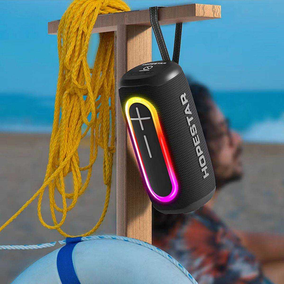 Hopestar P60 Outdoor Bluetooth Speaker hanging on a wooden post near the beach, featuring waterproof and portable design.