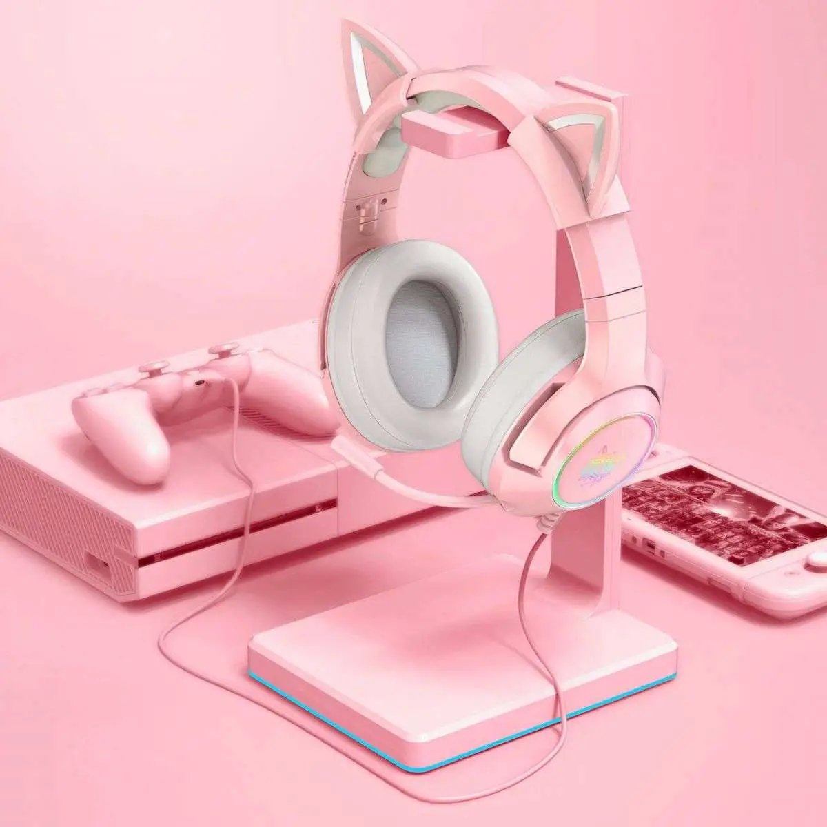 Pink ONIKUMA K9 Elite Gaming Headset displayed on a matching stand, alongside a gaming console and smartphone, showcasing its aesthetic appeal.