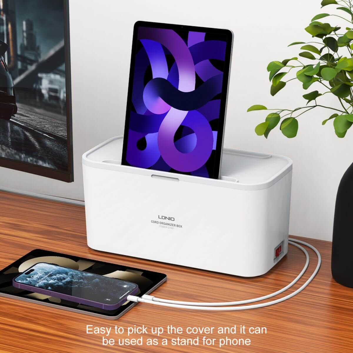 LDNIO SN5311 Power Strip Box used as a phone stand while charging, offering a multifunctional design for workspace organization.