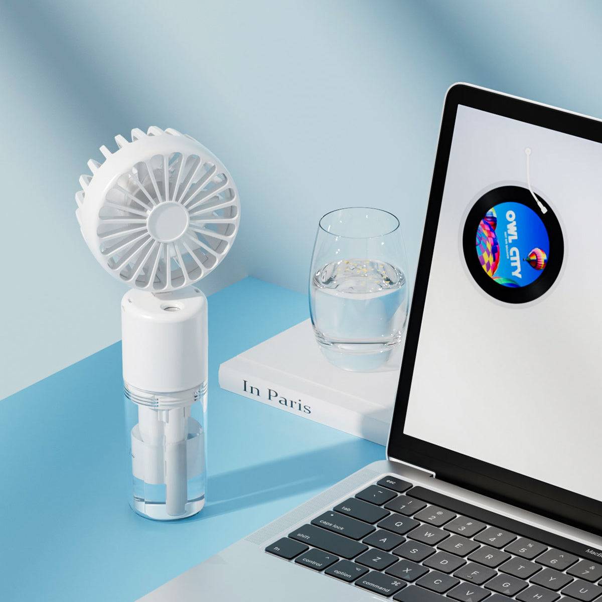 White F2 misting fan placed on a desk beside a laptop and water glass. Stylish and functional for indoor and office cooling.