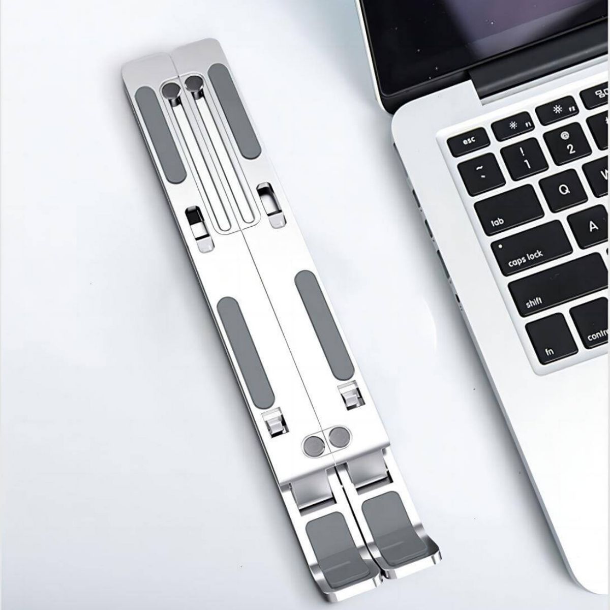 Folded Z34 Laptop Stand placed beside a laptop. Compact design ensures easy portability and storage in bags or backpacks.